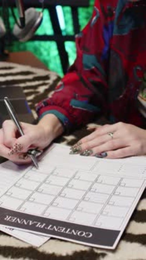 Person planerar innehåll i en kalender med penna vid ett skrivbord
